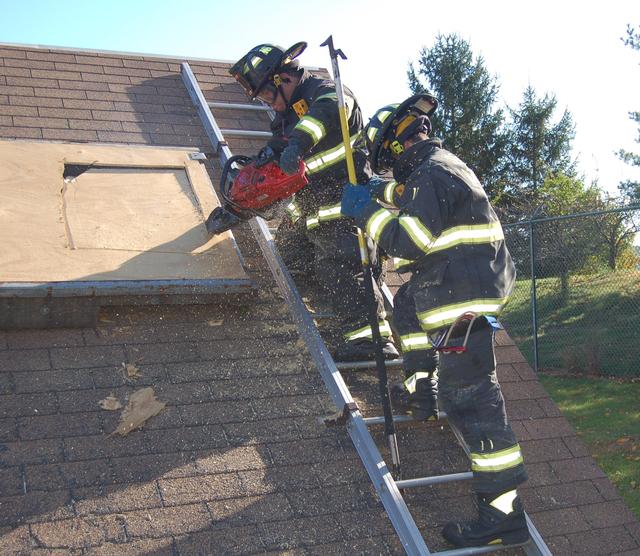 FF Lullo, backed up by FF/EMT Pirozzoli, uses the chainsaw to vent a roof, October 16, 2011.